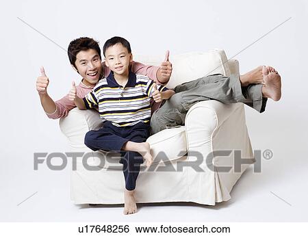 Portrait of a mid adult man sitting in an armchair with his son and showing thumbs up View Large Photo Image Stock Photograph - Portrait of a mid adult man sitting in an armchair with his son and showing thumbs up. Fotosearch