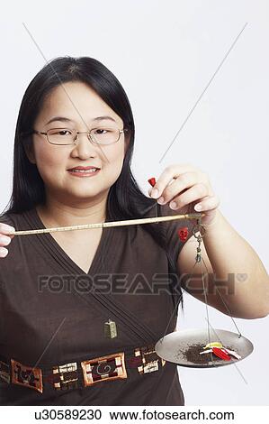 Stock Image - Portrait of a mid adult woman holding petals on a weighing scale. Fotosearch