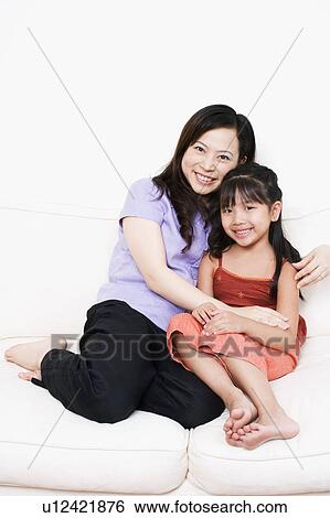 Portrait of a mother sitting on a couch with her daughter View Large Photo Image Stock Photograph - Portrait of a mother sitting on a couch with her daughter. Fotosearch