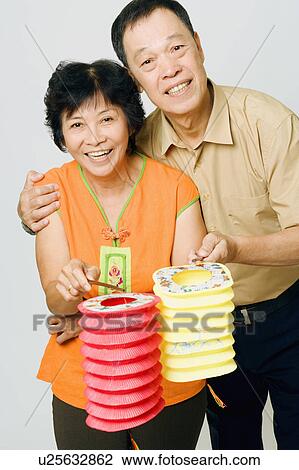 Stock Image - Portrait of a senior man and a mature woman holding Chinese lanterns. Fotosearch