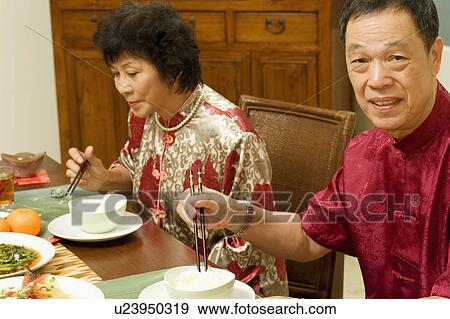 Portrait of a senior man sitting at a dining table with a mature woman beside him View Large Photo Image Stock Photo - Portrait of a senior man sitting at a dining table with a mature woman beside him. Fotosearch