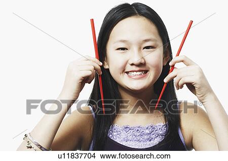 Portrait of a teenage girl holding chopsticks View Large Photo Image Picture - Portrait of a teenage girl holding chopsticks. Fotosearch