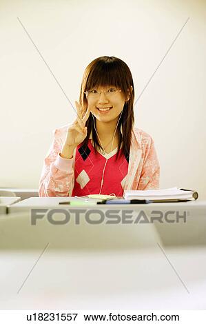 Stock Photo - Portrait of a teenage girl making a peace sign in the classroom. Fotosearch