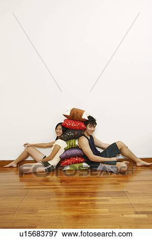 Portrait of a young couple sitting and leaning against a stack of cushions View Large Photo Image Stock Photo - Portrait of a young couple sitting and leaning against a stack of cushions. Fotosearch