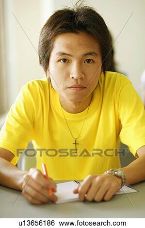 Portrait of a young man holding a pen on a notepad View Large Photo Image Stock Photograph - Portrait of a young man holding a pen on a notepad. Fotosearch