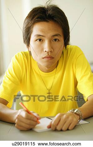 Stock Photography - Portrait of a young man holding a pen on a notepad. Fotosearch
