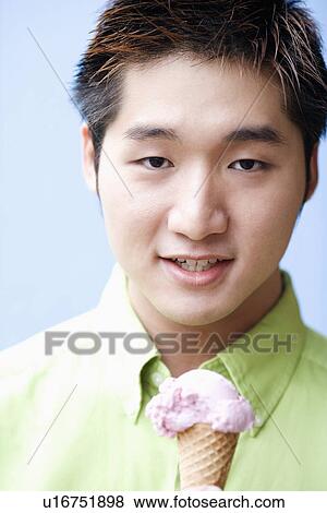 Portrait of a young man holding an ice-cream cone View Large Photo Image Stock Photo - Portrait of a young man holding an ice-cream cone. Fotosearch