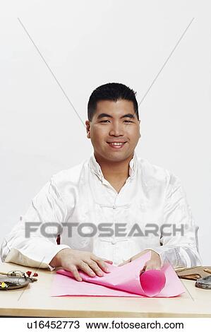 Stock Image - Portrait of a young man holding wrapping paper and smiling. Fotosearch