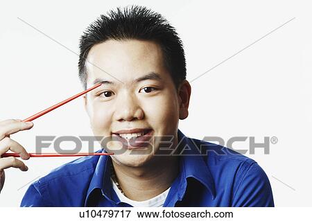 Portrait of a young man holding chopsticks View Large Photo Image Stock Photo - Portrait of a young man holding chopsticks. Fotosearch