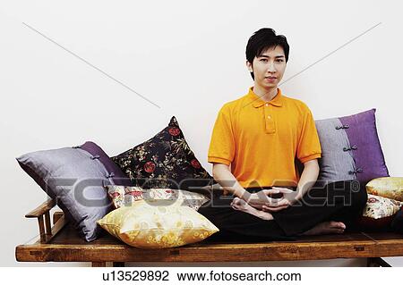 Stock Image - Portrait of a young man sitting on a bench. Fotosearch