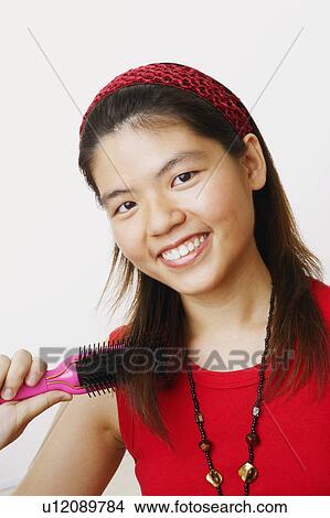 Portrait of a young woman brushing her hair and smiling View Large Photo Image Picture - Portrait of a young woman brushing her hair and smiling. Fotosearch