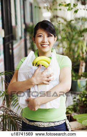 Portrait of a young woman carrying a plastic bag with bananas View Large Photo Image Stock Photo - Portrait of a young woman carrying a plastic bag with bananas. Fotosearch