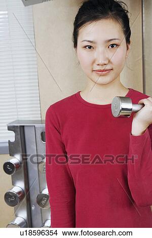 Picture - Portrait of a young woman exercising with dumbbells. Fotosearch