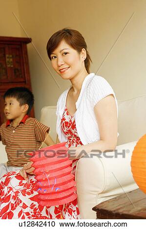 Portrait of a young woman holding a Chinese lantern with her son beside her View Large Photo Image Stock Image - Portrait of a young woman holding a Chinese lantern with her son beside her. Fotosearch