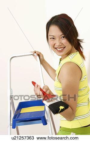 Stock Image - Portrait of a young woman holding a paintbrush. Fotosearch