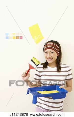 Portrait of a young woman holding a paint tray with a paintbrush and smiling View Large Photo Image Stock Photo - Portrait of a young woman holding a paint tray with a paintbrush and smiling. Fotosearch