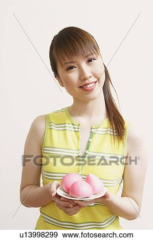 Portrait of a young woman holding a plate of fruit View Large Photo Image Stock Photo - Portrait of a young woman holding a plate of fruit. Fotosearch