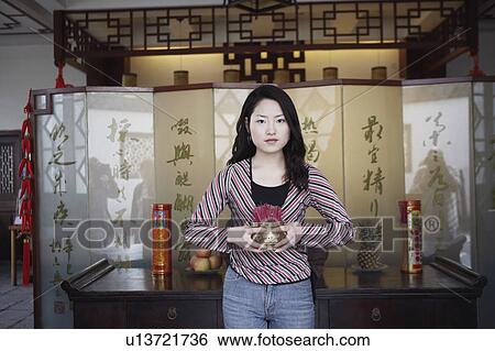 Portrait of a young woman holding a bowl of incense sticks View Large Photo Image Stock Photograph - Portrait of a young woman holding a bowl of incense sticks. Fotosearch