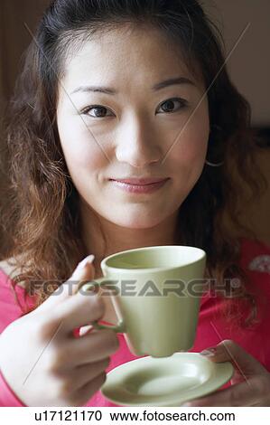 Portrait of a young woman holding a tea cup View Large Photo Image Stock Image - Portrait of a young woman holding a tea cup. Fotosearch