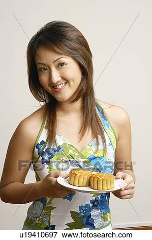 Portrait of a young woman holding cup cakes in a plate View Large Photo Image Stock Photo - Portrait of a young woman holding cup cakes in a plate. Fotosearch