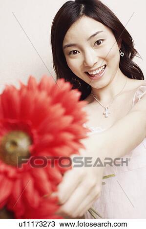 Stock Image - Portrait of a young woman holding flowers. Fotosearch