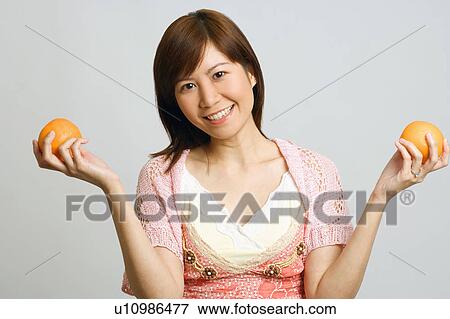 Stock Photo - Portrait of a young woman holding oranges. Fotosearch