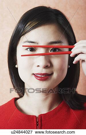Portrait of a young woman holding chopsticks in front of her face View Large Photo Image Stock Photo - Portrait of a young woman holding chopsticks in front of her face. Fotosearch