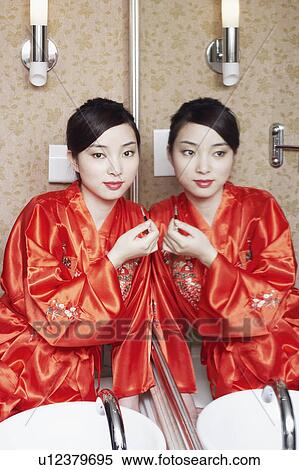 Stock Photography - Portrait of a young woman holding lipstick. Fotosearch