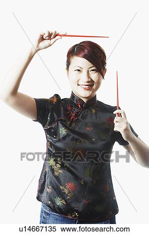 Stock Photography - Portrait of a young woman holding chopsticks. Fotosearch