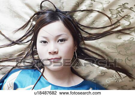 Stock Image - Portrait of a young woman lying on her back. Fotosearch