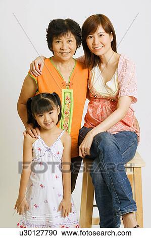 Portrait of a young woman sitting on a stool with her mother and her daughter standing beside her View Large Photo Image Stock Image - Portrait of a young woman sitting on a stool with her mother and her daughter standing beside her. Fotosearch