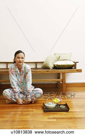 Portrait of a young woman sitting on a hardwood floor View Large Photo Image Stock Photo - Portrait of a young woman sitting on a hardwood floor. Fotosearch