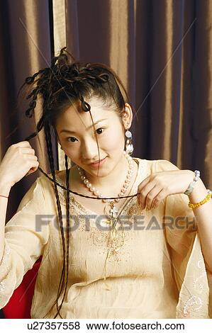 Portrait of a young woman sitting on a chair View Large Photo Image Stock Photo - Portrait of a young woman sitting on a chair. Fotosearch