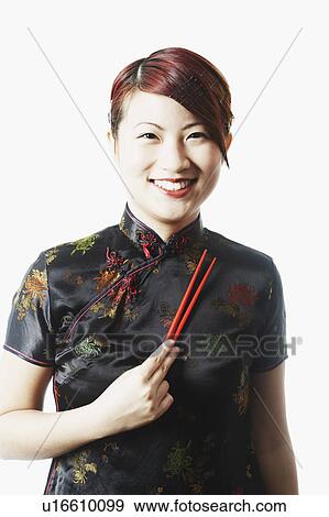 Portrait of a young woman smiling and holding chopsticks View Large Photo Image Stock Photo - Portrait of a young woman smiling and holding chopsticks. Fotosearch