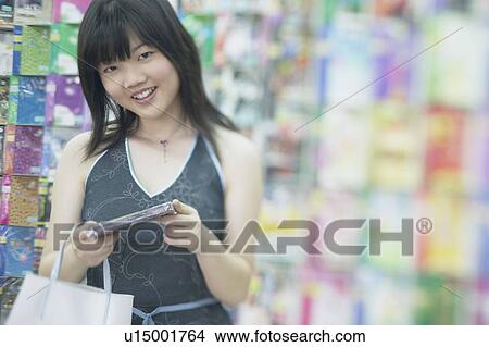 Picture - Portrait of a young woman standing in a record store. Fotosearch
