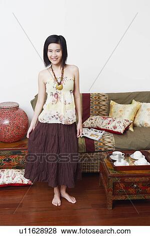 Portrait of a young woman standing in a room and smiling View Large Photo Image Stock Photo - Portrait of a young woman standing in a room and smiling. Fotosearch