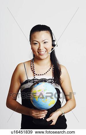 Portrait of a young woman wearing a headset and holding a globe View Large Photo Image Stock Photo - Portrait of a young woman wearing a headset and holding a globe. Fotosearch