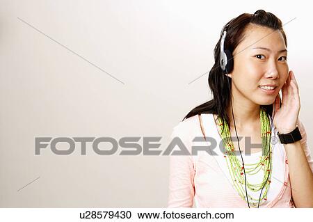 Stock Image - Portrait of a young woman wearing headphones and smiling. Fotosearch