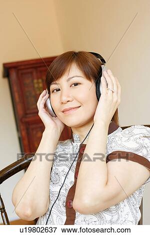 Portrait of a young woman wearing headphones and listening to music View Large Photo Image Stock Photo - Portrait of a young woman wearing headphones and listening to music. Fotosearch