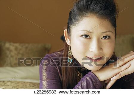 Stock Image - Portrait of a young woman with her hand on her chin smiling. Fotosearch