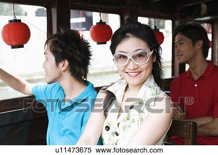 Stock Photography - Portrait of a young woman with two young men traveling in a tourboat. Fotosearch