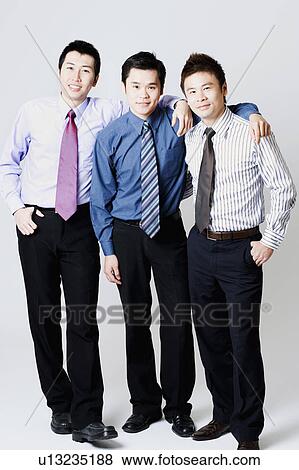 Portrait of three businessmen standing and smiling View Large Photo Image Stock Photo - Portrait of three businessmen standing and smiling. Fotosearch