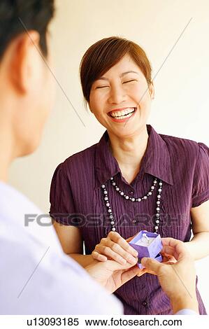 Stock Photography - Rear view of a young man offering a ring to a young woman. Fotosearch
