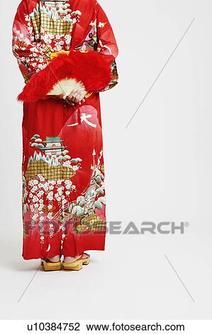 Rear view of a young woman standing and holding a feather fan View Large Photo Image Stock Image - Rear view of a young woman standing and holding a feather fan. Fotosearch