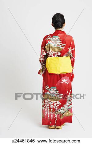 Rear view of a young woman standing and wearing traditional clothing View Large Photo Image Stock Photograph - Rear view of a young woman standing and wearing traditional clothing. Fotosearch