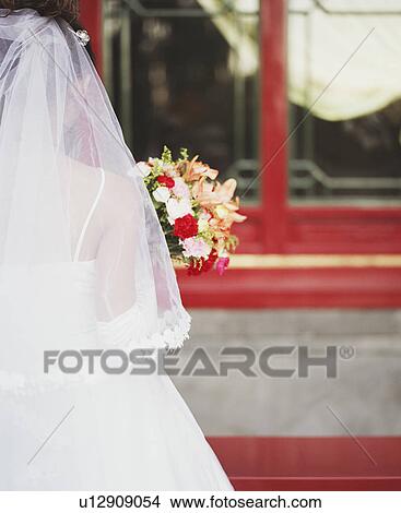 Picture - Rear view of young woman in the wedding dress holding flowers. Fotosearch