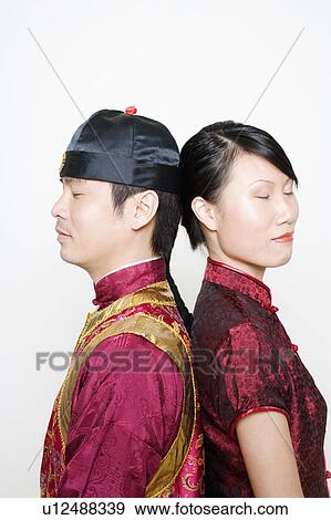 Stock Photo - Side profile of a young man and a young woman standing back to back with their eyes closed. Fotosearch