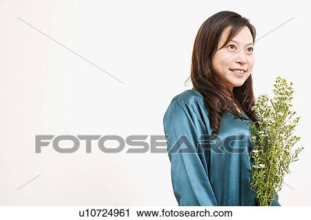Side profile of a young woman holding a plant and smiling View Large Photo Image Stock Image - Side profile of a young woman holding a plant and smiling. Fotosearch
