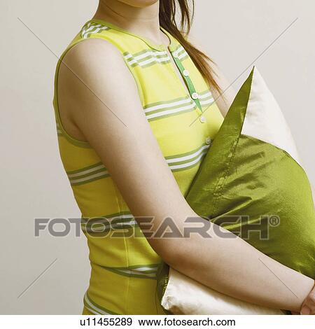 Side profile of a young woman holding a cushion and smiling View Large Photo Image Stock Photo - Side profile of a young woman holding a cushion and smiling. Fotosearch