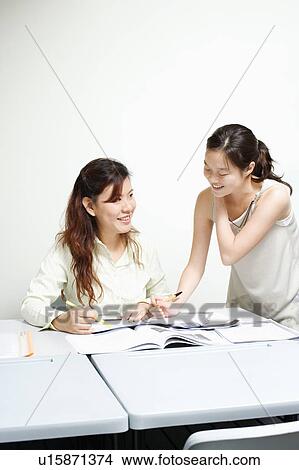 Teacher teaching a young woman in a classroom View Large Photo Image Picture - Teacher teaching a young woman in a classroom. Fotosearch